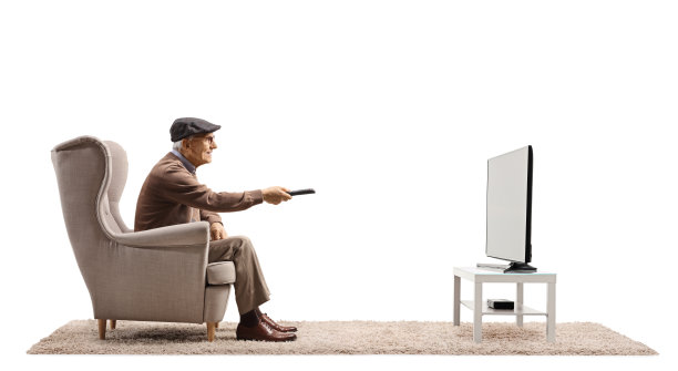 一位老人坐在扶手椅上用遥控器换电视频道图片下载