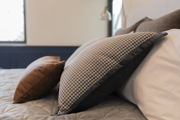 美容室的床上铺着干净的白色枕头和床单。特写镜头。镜头在阳光下的天赋。新床被与装饰枕头，床头板在卧室在家里分期特写图片下载