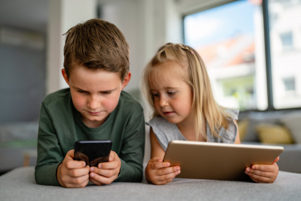 小孩子拿着智能手机、平板电脑玩手机在线游戏，孩子和小玩意的概念图片下载