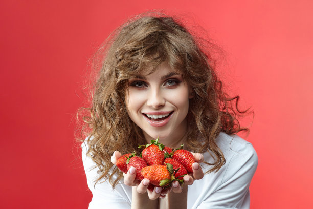 迷人的女孩微笑着，手里拿着一把草莓。图片下载