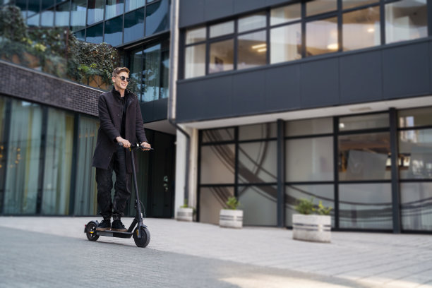 年轻优雅的男人穿着大衣，开着摩托车穿过城市图片下载