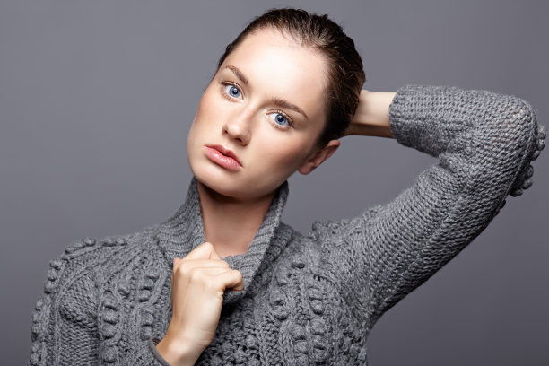 美丽肖像的年轻女子在灰色羊毛毛衣。深色头发的女孩，明亮的蓝色眼睛和日间女性化妆图片下载
