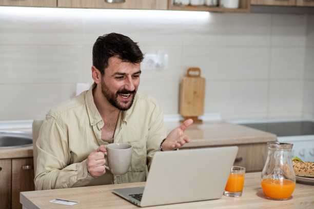 一个年轻人在他的家里微笑，同时进行视频通话图片下载