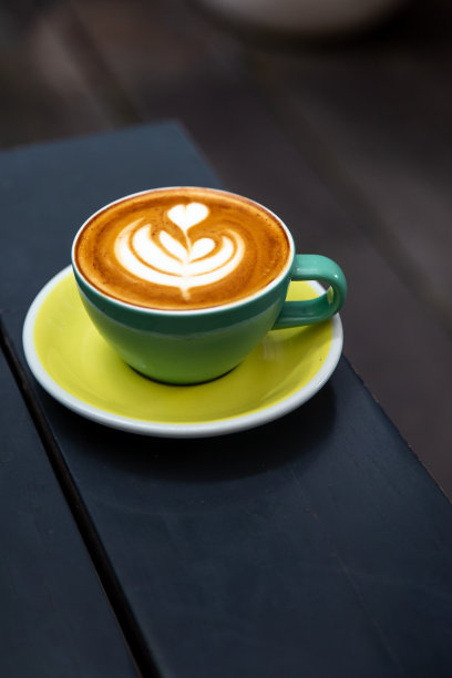 绿色的卡布奇诺杯与拿铁艺术在木制背景。图片下载