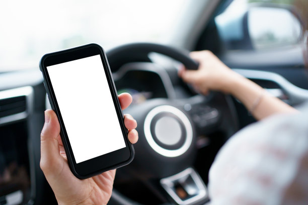 女性开车时使用智能手机。图片下载