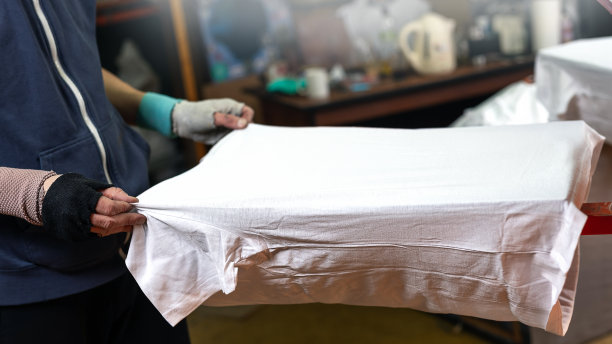 白色t恤在男性手中准备印刷。丝网印刷选择性对焦照片。在车间制作t恤印花。绢印生产图片下载