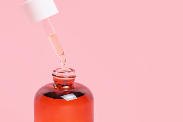 一个血清和滴管的粉红色背景特写，自然化妆品的概念图片下载