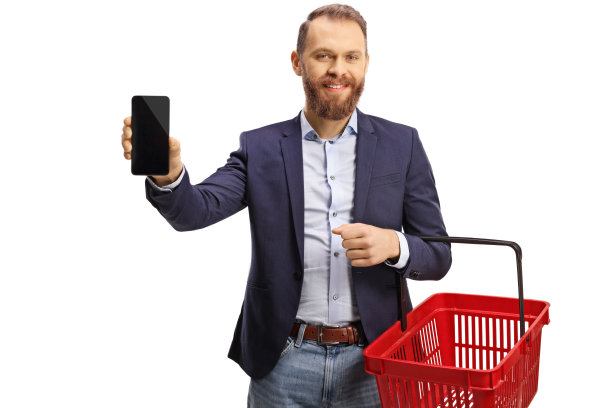 微笑的年轻人拿着一个空的购物篮和一个手机图片下载