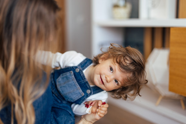 一个顽皮的学步儿童的照片，享受与他的妈妈，在家里。图片下载