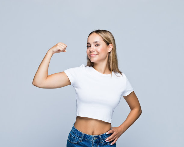 自信的女孩手放在臀部，秀肌肉图片下载