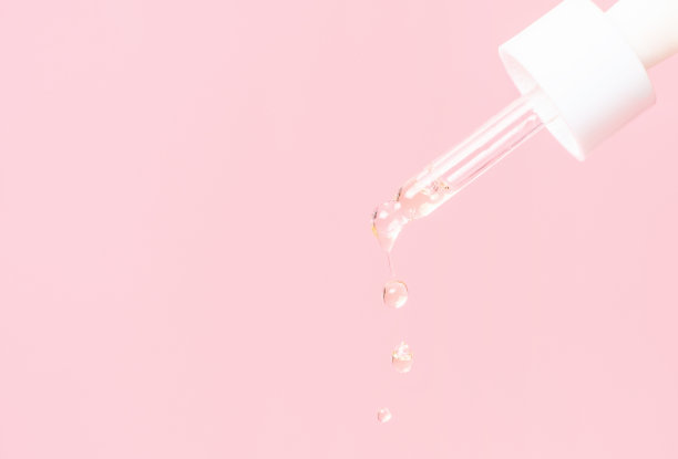 滴管与血清或胶原蛋白的粉红色背景特写。图片下载
