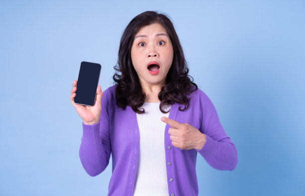 中年亚洲妇女肖像使用智能手机的蓝色背景图片下载