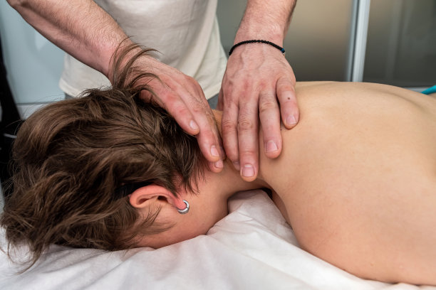 理疗师在做颈部按摩，年轻漂亮的女性客户在水疗沙龙图片下载