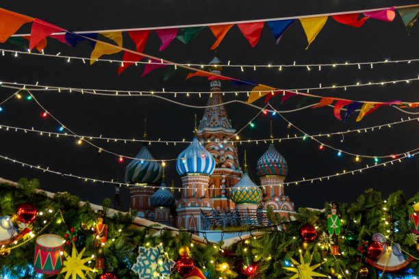位于莫斯科红场的圣巴西尔大教堂的夜景，为庆祝圣诞节和新年而装饰。彩旗和玩具悬挂在松树上。图片下载