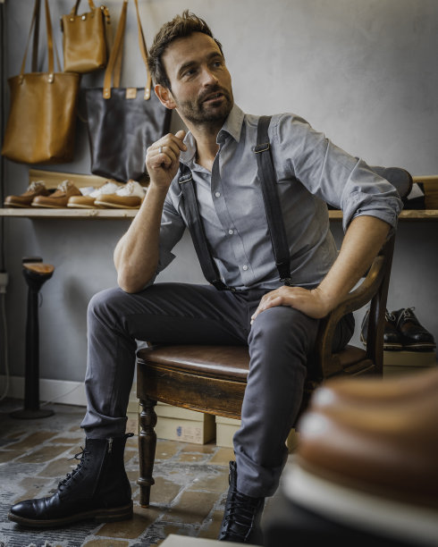 穿着灰色复古服装的男模特坐在椅子上摆姿势图片下载
