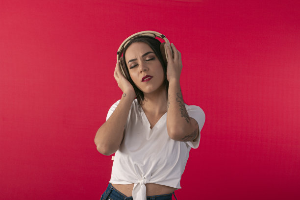年轻女子与耳机作为DJ和工作室照片的红色背景。图片下载