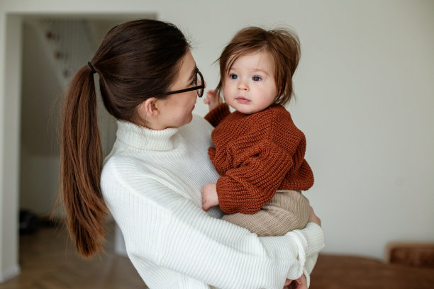 年轻的母亲怀抱着美丽的小女儿。母亲和8个月大的婴儿。图片下载