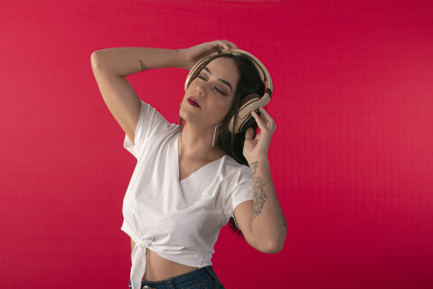 年轻女子与耳机作为DJ和工作室照片的红色背景。图片下载