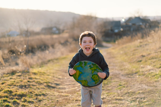 小男孩手里拿着星球，背景是绿色的春天图片下载