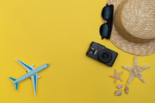 草帽，太阳镜和海星与相机的黄色背景图片下载