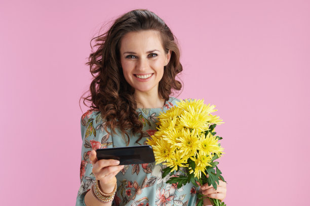 微笑的女人在花裙使用手机应用程序粉红图片下载