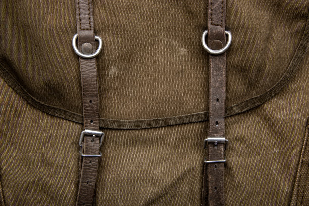 帆布背包特写纹理，配皮革带和金属扣，复古卡其色背景图片下载
