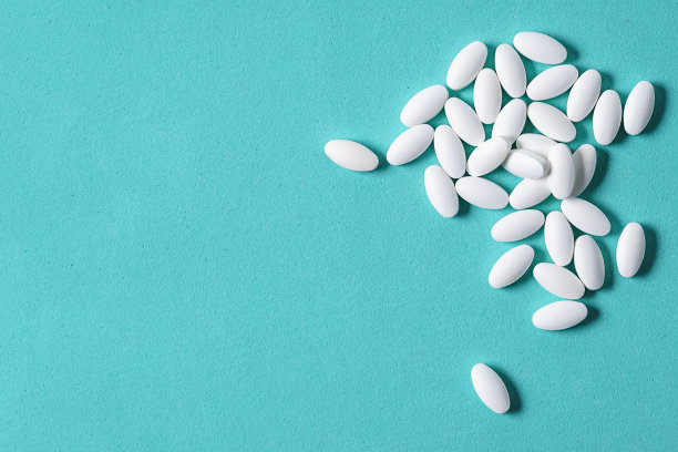 蓝色背景上白色椭圆形药片。带有复制空间的微距照片。图片下载