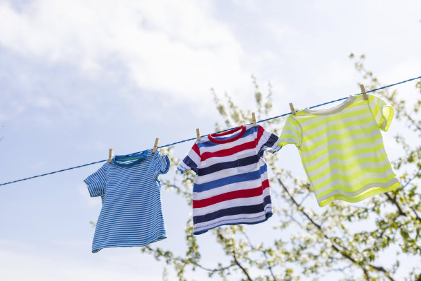 洗衣日在户外的绳子上把衣服洗干净。彩色t恤挂在晾衣绳上，映衬着蓝天图片下载