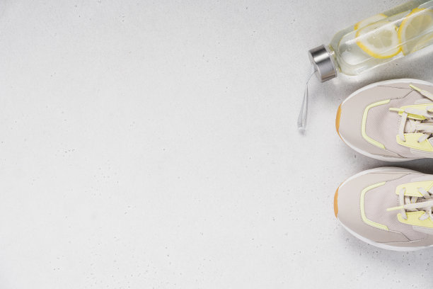 清新的水与柠檬在玻璃瓶和运动鞋浅灰色的背景与拷贝空间，俯视图图片下载