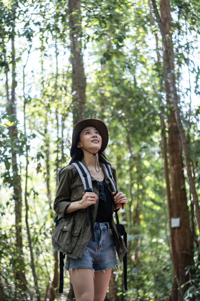 亚洲年轻美丽的女性背包客独自在野生森林旅行。迷人的女孩旅行者环顾四周，探索，漫步在自然的木材与幸福和乐趣的假期旅行。图片下载
