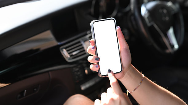 年轻人坐在车里看智能手机导航。图片下载