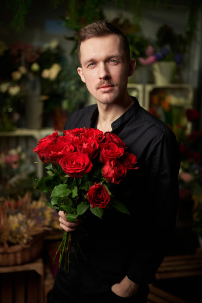 浪漫的男子在黑色衬衫与红玫瑰花束图片下载