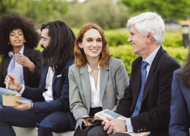 同事们，不同年龄的老男人和年轻女人坐在城市的街道上吃午饭，同事们在后面图片下载