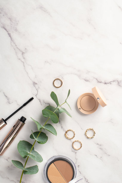 化妆的概念。俯视图垂直的照片轮廓调色板，眼影，睫毛膏，黄金戒指和桉树在白色大理石的背景与copyspace图片下载