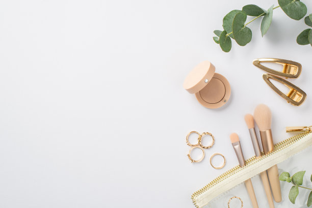 美丽的概念。顶视图照片的金发夹环眼影化妆刷透明化妆袋和桉树在孤立的白色背景与copyspace图片下载