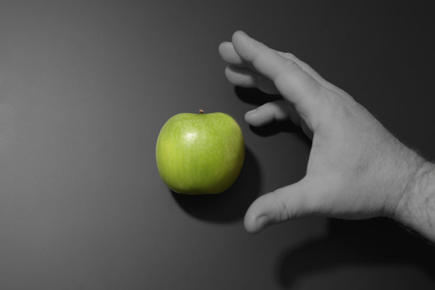 一个男人的手伸向一个青苹果。黑白拼贴。生态主题图片下载