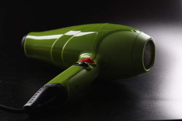 绿色电吹风，全新的装置放在黑暗的背景上，仪器为美容大师图片下载