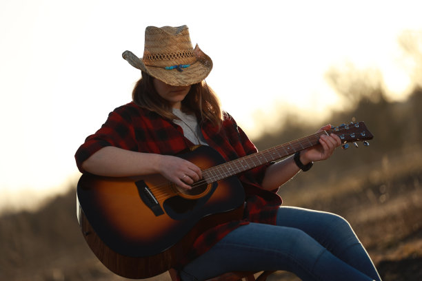 牛仔女郎在日落时弹吉他图片下载