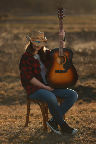 牛仔女郎在日落时弹吉他图片下载