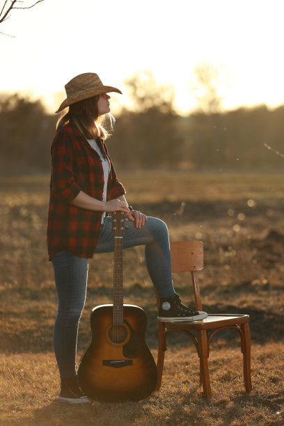 牛仔女郎在日落时弹吉他图片下载