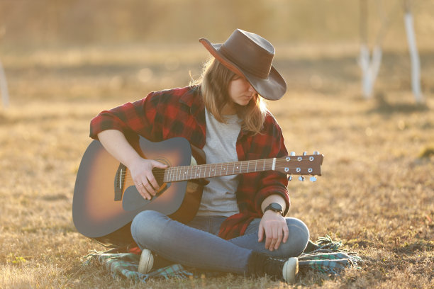 牛仔女郎在日落时弹吉他图片下载