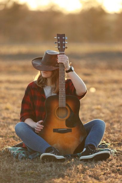 牛仔女郎在日落时弹吉他图片下载