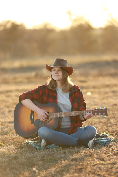 牛仔女郎在日落时弹吉他图片下载