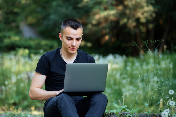 年轻的自由职业者在公园用笔记本电脑工作图片下载