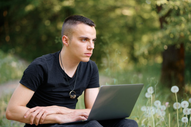 年轻的自由职业者在公园用笔记本电脑工作图片下载