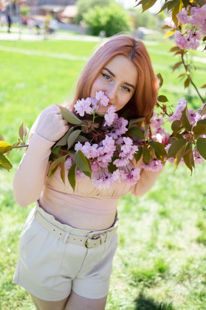 春天花园里美丽的年轻女子。女孩附近的樱花图片下载