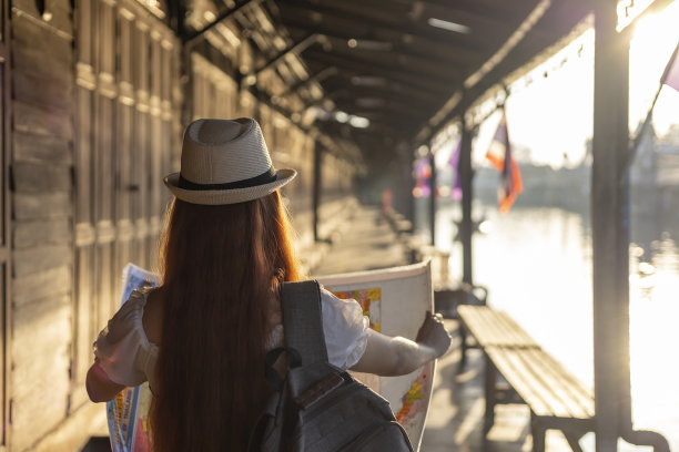 一名亚洲女性正在东南亚的泰国旅行，她在没有手机应用的情况下，用纸质地图定位目的地，享受当地宁静村庄的生活氛围图片下载