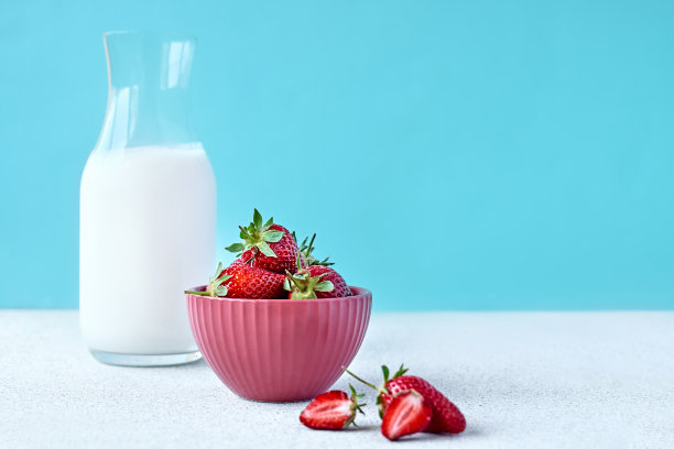 草莓椰子奶昔，frappé或奶昔在淡蓝色的背景上饮用玻璃杯。健康的纯素饮食清爽饮料。健康饮食理念。图片下载