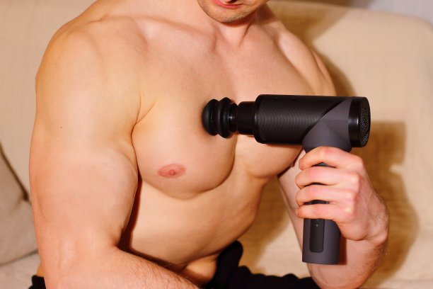 运动男子在家使用按摩枪图片下载