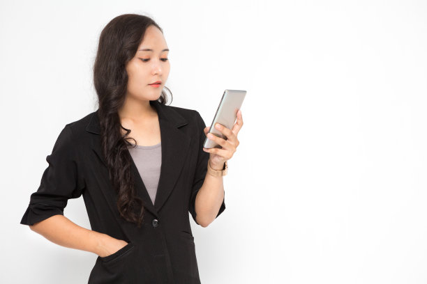 美丽的亚洲商业女性穿着黑色西装拿着智能手机在白色背景和拷贝空间。自信的亚洲职业女性微笑，开朗图片下载
